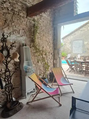 two chairs and a refrigerator on a patio at La maisonnette avec SPA, PISCINE et CLIMATISATION in Sainte-Vallière