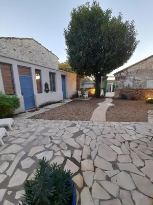 a stone patio with a tree and a house at La maisonnette avec SPA, PISCINE et CLIMATISATION in Sainte-Vallière