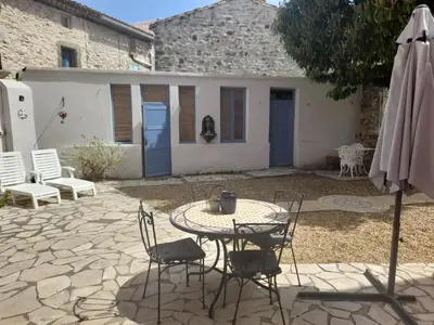 a patio with a table and chairs and an umbrella at La maisonnette avec SPA, PISCINE et CLIMATISATION in Sainte-Vallière