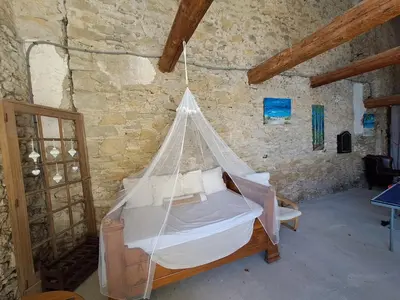 a hammock bed in a room with a stone wall at La maisonnette avec SPA, PISCINE et CLIMATISATION in Sainte-Vallière