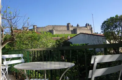 a table and chairs on a balcony with a castle at La Villa Carcassonne, Chambres d hôtes, B&B, face à la Cité Médiévale in Carcassonne
