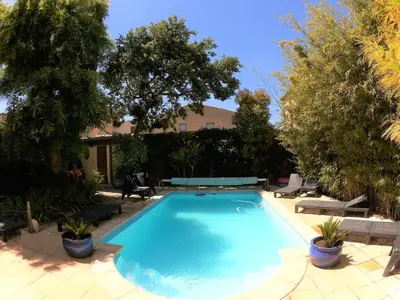a large blue swimming pool in a yard with trees at La Villa Carcassonne, Chambres d hôtes, B&B, face à la Cité Médiévale in Carcassonne