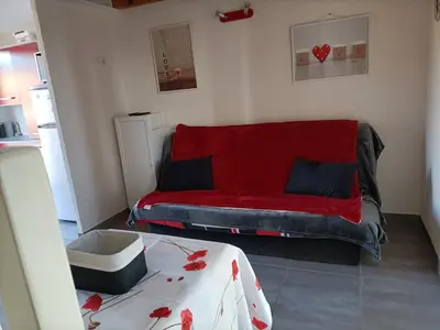 a living room with a red couch and a table at L'Appart de Karine et Nico in Gruissan