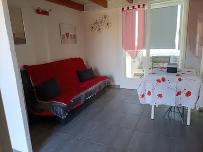 a living room with a red couch and a table at L'Appart de Karine et Nico in Gruissan