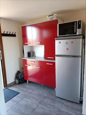 a kitchen with red cabinets and a microwave on top of a refrigerator at L'Appart de Karine et Nico in Gruissan