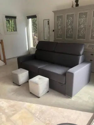 a living room with a black couch and two stools at Gîte la Lezardière accès privé canal du midi ** in Castelnaudary
