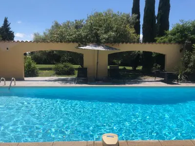 a blue swimming pool with an umbrella and trees at Gîte la Lezardière accès privé canal du midi ** in Castelnaudary