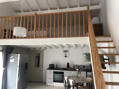 a kitchen with a loft bed and a kitchen with a table at Gîte la Lezardière accès privé canal du midi ** in Castelnaudary