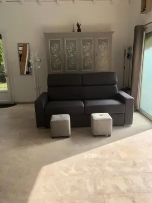 a living room with a black couch and two stools at Gîte la Lezardière accès privé canal du midi ** in Castelnaudary