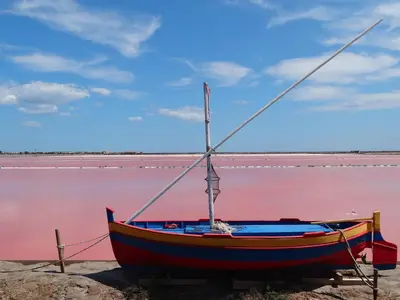 a boat sitting on the shore of a pink lake at studio gruissan proche plage des chalets in Gruissan