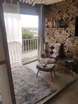 a living room with a chair and a balcony at studio gruissan proche plage des chalets in Gruissan