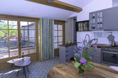a kitchen with a table with a vase of flowers on it at Cottage - La Maison du Château - By DOMAINE RIBERACH in Bélesta