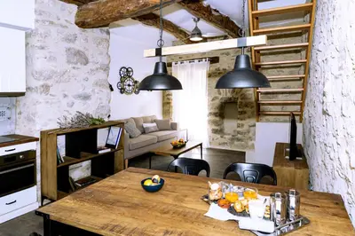 a kitchen and living room with a wooden table at Cottage - La Maison du Château - By DOMAINE RIBERACH in Bélesta