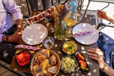 a group of people sitting around a table with food at Cottage - La Maison du Château - By DOMAINE RIBERACH in Bélesta