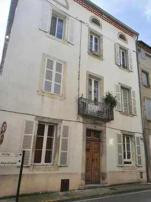 a white building with a wooden door and windows at Maison Carrasserie in Limoux