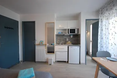 a kitchen with white cabinets and a table in a room at Saphir de Gruissan in Gruissan