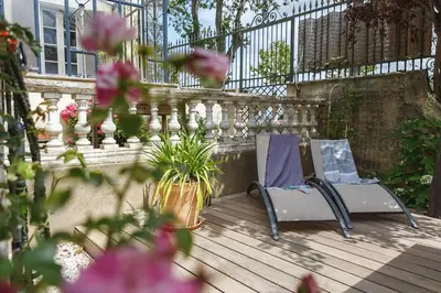 two chairs on a deck with a fence and flowers at LaFabriek in Canet d'Aude