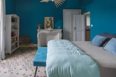 a bedroom with blue walls and a bed and a chair at LaFabriek in Canet d'Aude