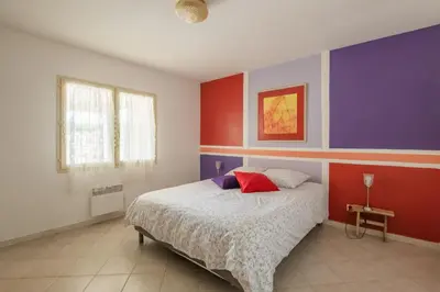 a bedroom with a bed with red and purple walls at Villa les cigales in Ouveillan