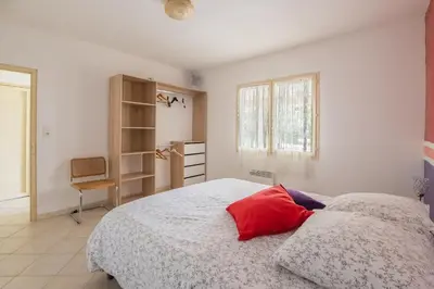 a bedroom with a bed with a red pillow on it at Villa les cigales in Ouveillan