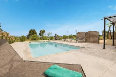 a large swimming pool with a patio at Villa les cigales in Ouveillan