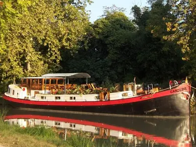 a boat on a river with trees in the background at Peniche Caroline in Capestang
