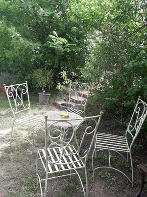 three chairs and a table in a yard with trees at Peniche Caroline in Capestang