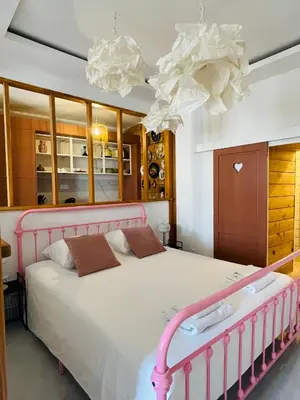 a bedroom with a pink bed and a chandelier at Le trois nourrices in Narbonne
