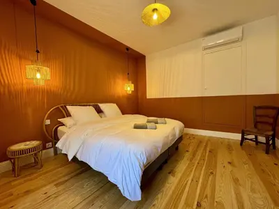 a bedroom with a large bed and a chair at L'Oustal de Papet in Ferrals-lès-Corbières