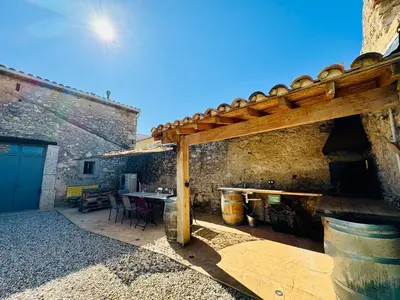 an outdoor patio with a wooden pergola and a table at L'Oustal de Papet in Ferrals-lès-Corbières