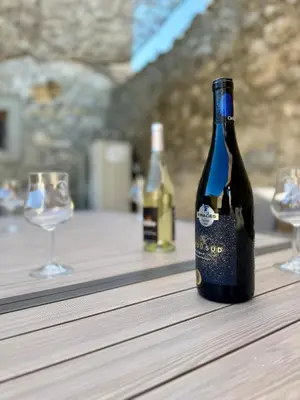 a bottle of wine sitting on a table with two glasses at L'Oustal de Papet in Ferrals-lès-Corbières