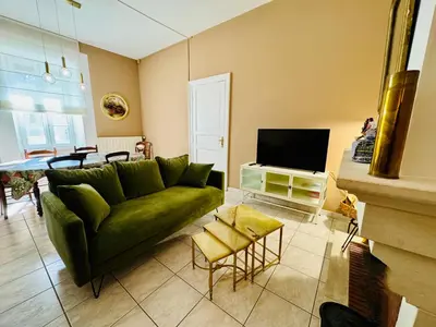 a living room with a green couch and a tv at L'Oustal de Papet in Ferrals-lès-Corbières