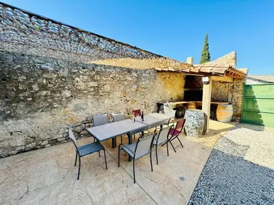 a table and chairs in front of a stone wall at L'Oustal de Papet in Ferrals-lès-Corbières