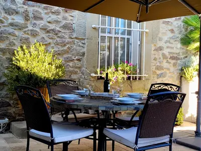 a table with chairs and an umbrella on a patio at Demeure vigneronne de charme Pays CATHARE Carcassonne Jacuzzi in Blomac