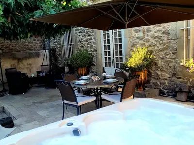 a hot tub in a patio with a table and chairs at Demeure vigneronne de charme Pays CATHARE Carcassonne Jacuzzi in Blomac