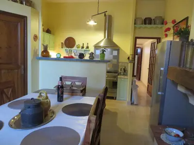 a kitchen with a table and a refrigerator at Demeure vigneronne de charme Pays CATHARE Carcassonne Jacuzzi in Blomac
