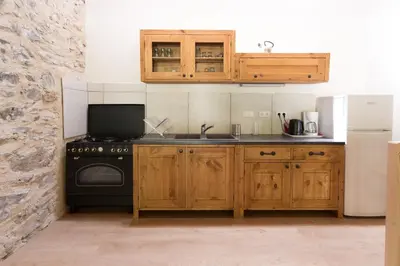 a kitchen with wooden cabinets and a black stove at Gîtes du Pont de Calmel in Rieussec