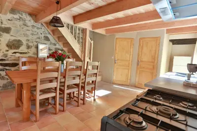 a kitchen with a stove and a table and chairs at Gîtes du Pont de Calmel in Rieussec
