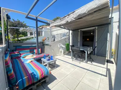 a balcony with a bed and a table on a patio at La Maison Bleue in Gruissan