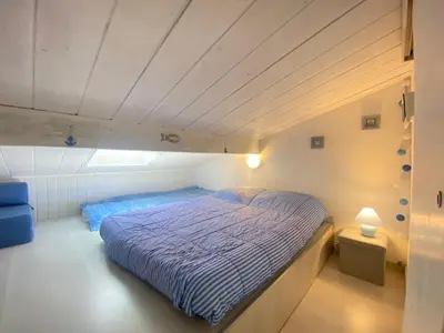 a bedroom with a bed with a blue comforter at La Maison Bleue in Gruissan