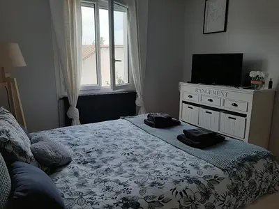 a bedroom with a bed with a tv and a dresser at Chambre double dans maison chaleureuse et familiale in Carcassonne