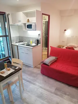 a living room with a red couch and a kitchen at Charmant logis au coeur de Mirepoix in Mirepoix