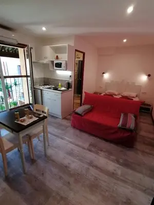 a living room with a red bed and a table at Charmant logis au coeur de Mirepoix in Mirepoix