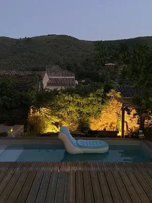 a swimming pool with a lounge chair sitting on a deck at MAISON ST LAURENT in Olargues