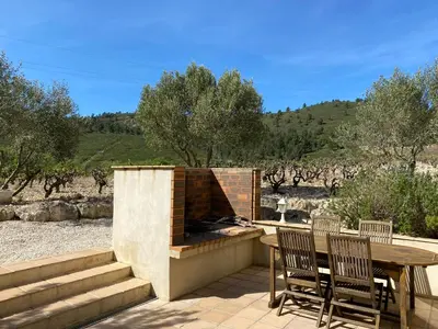 a patio with a fireplace and a table and chairs at Les Plages Haute in Peyriac-de-Mer