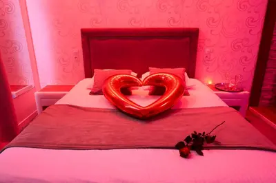 a red bed with a heart shaped pillow on it at Le DONJON DIONYSOS - Love Room in Carcassonne