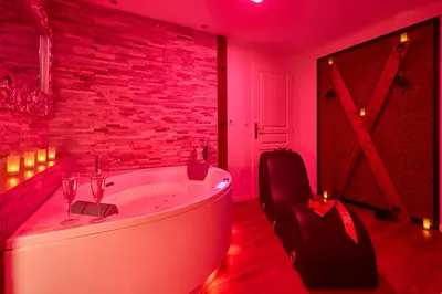 a bathroom with a white tub in a red room at Le DONJON DIONYSOS - Love Room in Carcassonne