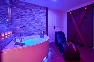 a bath tub in a room with a brick wall at Le DONJON DIONYSOS - Love Room in Carcassonne
