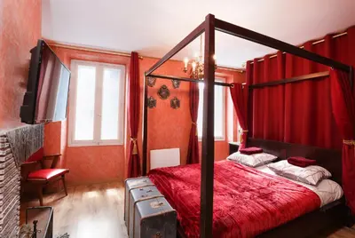 a bedroom with a canopy bed with red curtains at HARRY POTTER - Escape Game - Expérience Magique in Carcassonne