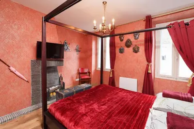 a bedroom with red walls and a bed with a red bedspread at HARRY POTTER - Escape Game - Expérience Magique in Carcassonne